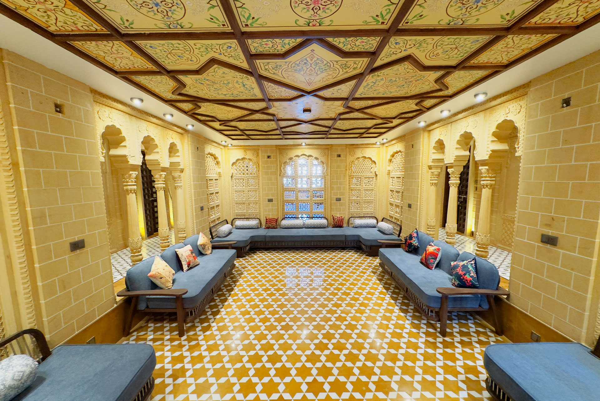 Spacious indoor lounge with carved sandstone arches at Guulab Haveli