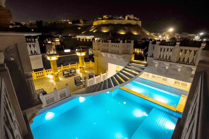 Illuminated Jaisalmer Fort viewed across the rooftop pool